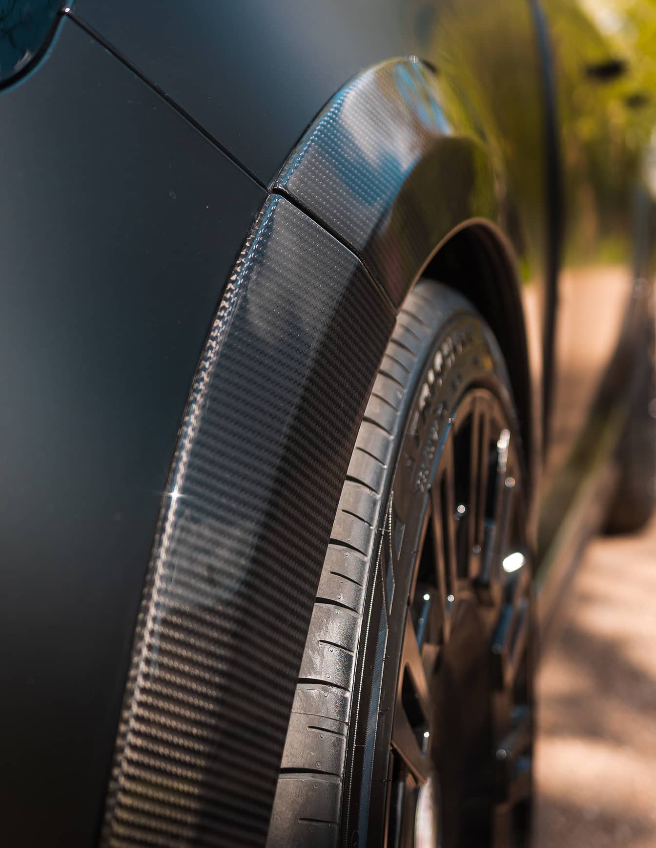 A custom Forge Land Rover Range Rover with a carbon fiber wheel arch and tire on a sunny day.