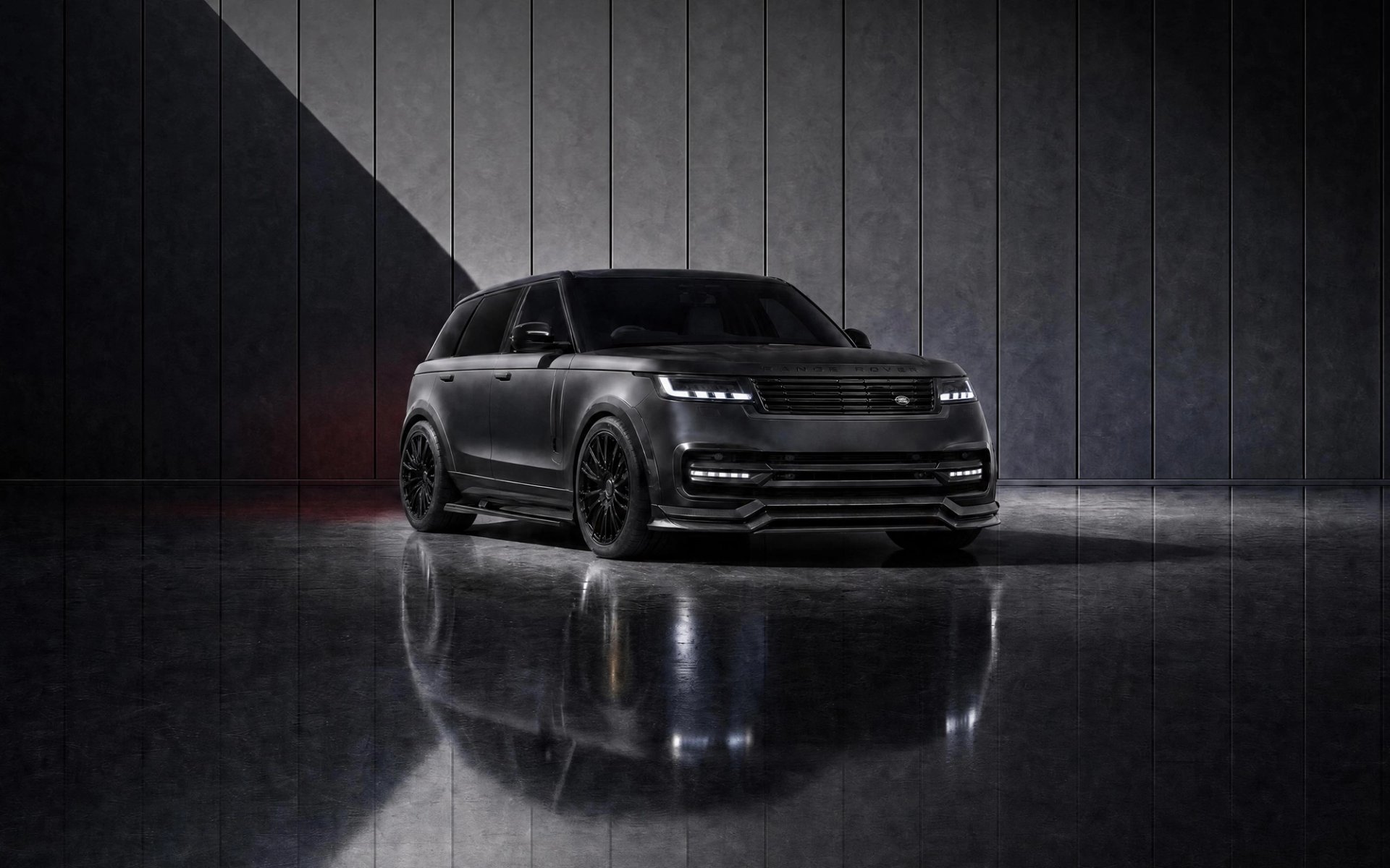A custom Forge Land Rover Range Rover in matte black is parked on a reflective floor against a textured gray wall.