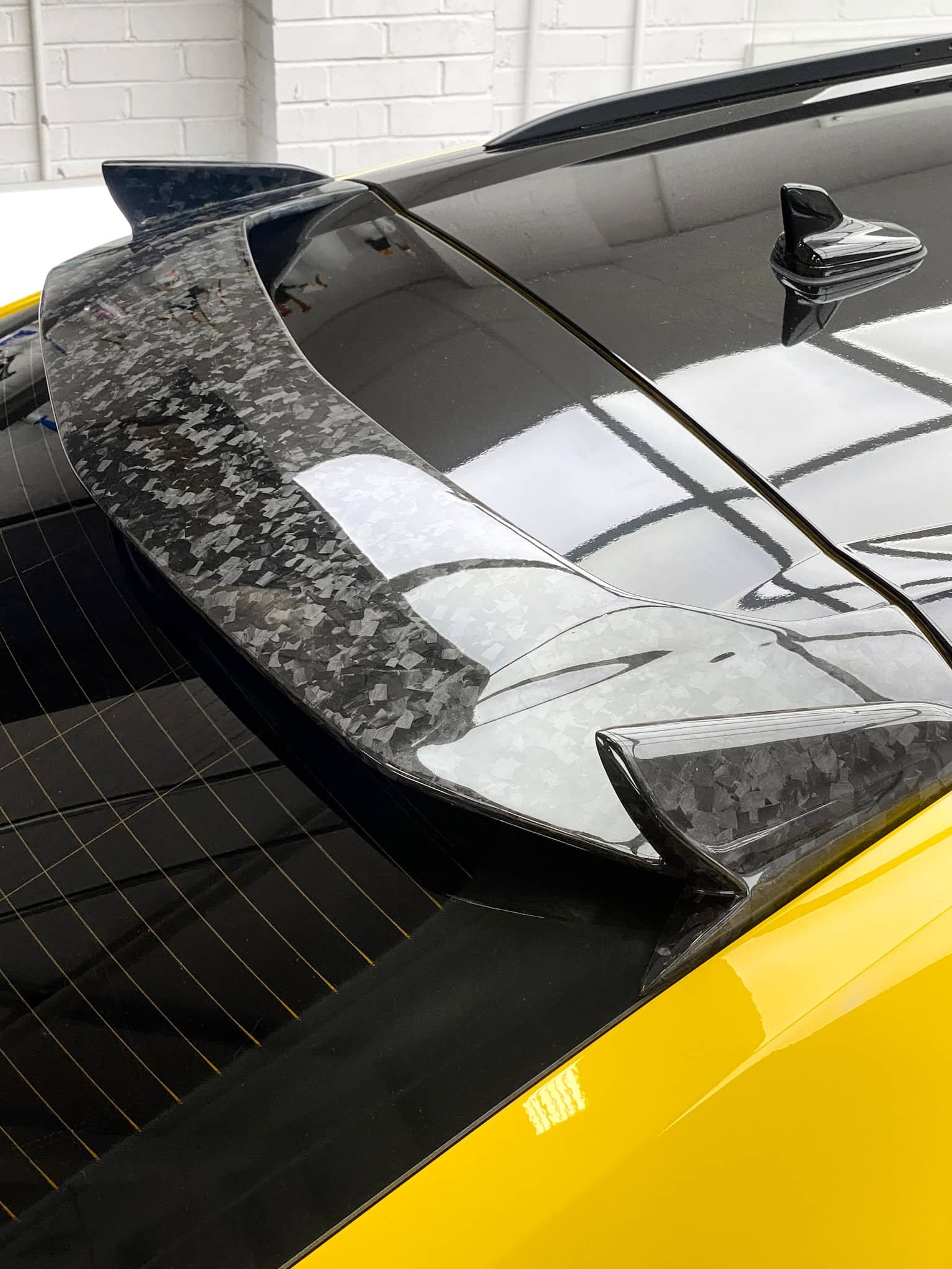 A close-up of the forged carbon fiber rear spoiler on a custom Forge Lamborghini Urus inside a workshop.