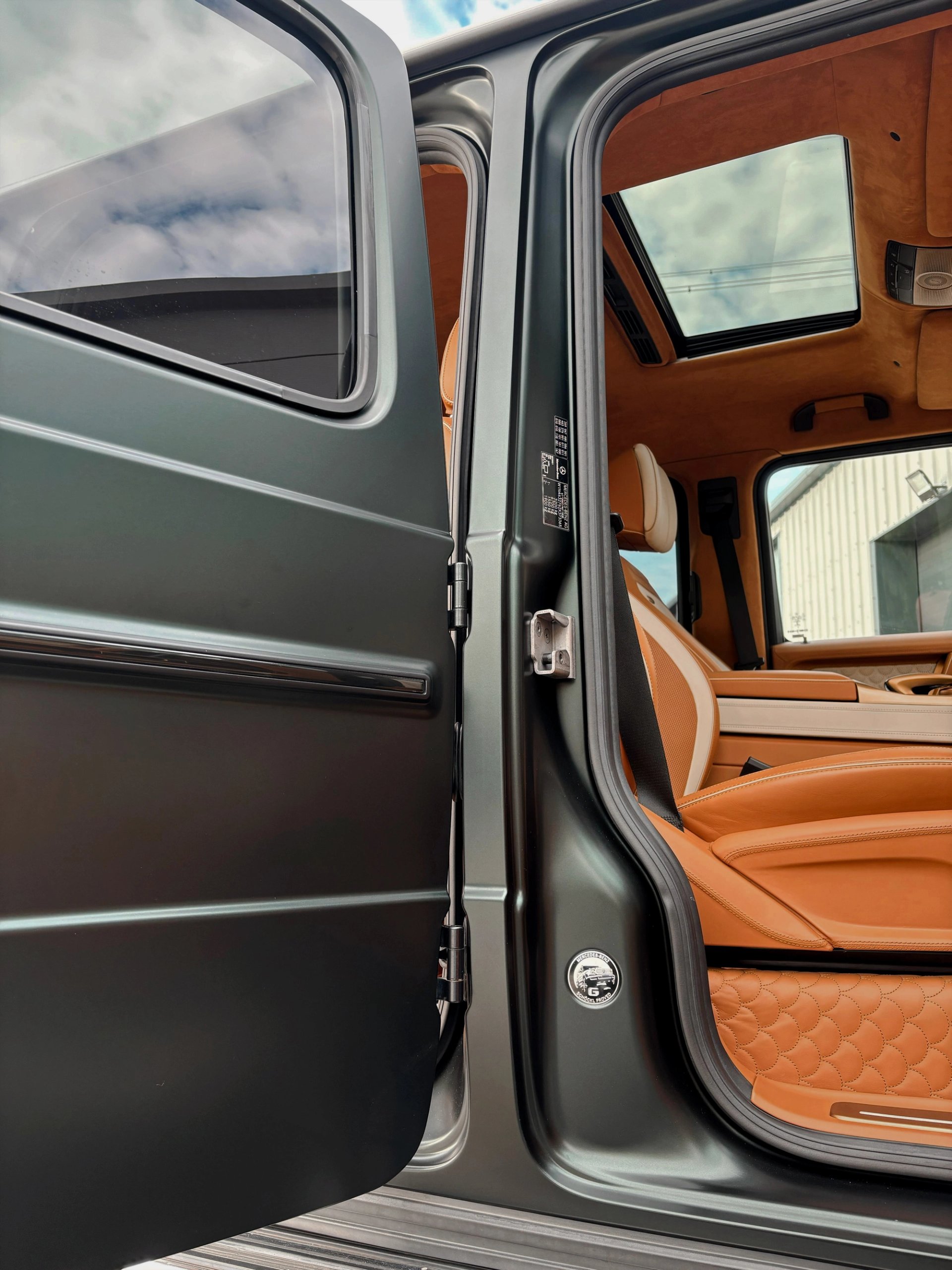 An open door of a custom Forge Mercedes G63 reveals a tan leather interior and a sunroof.