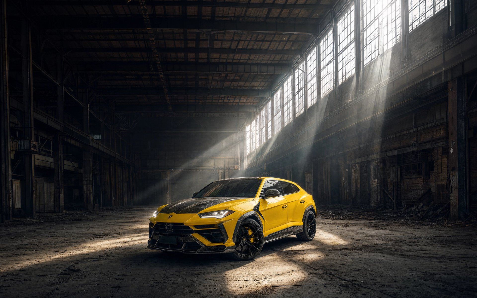 A yellow custom Forge Lamborghini Urus parked inside a rustic warehouse as dramatic sunlight streams through high windows.