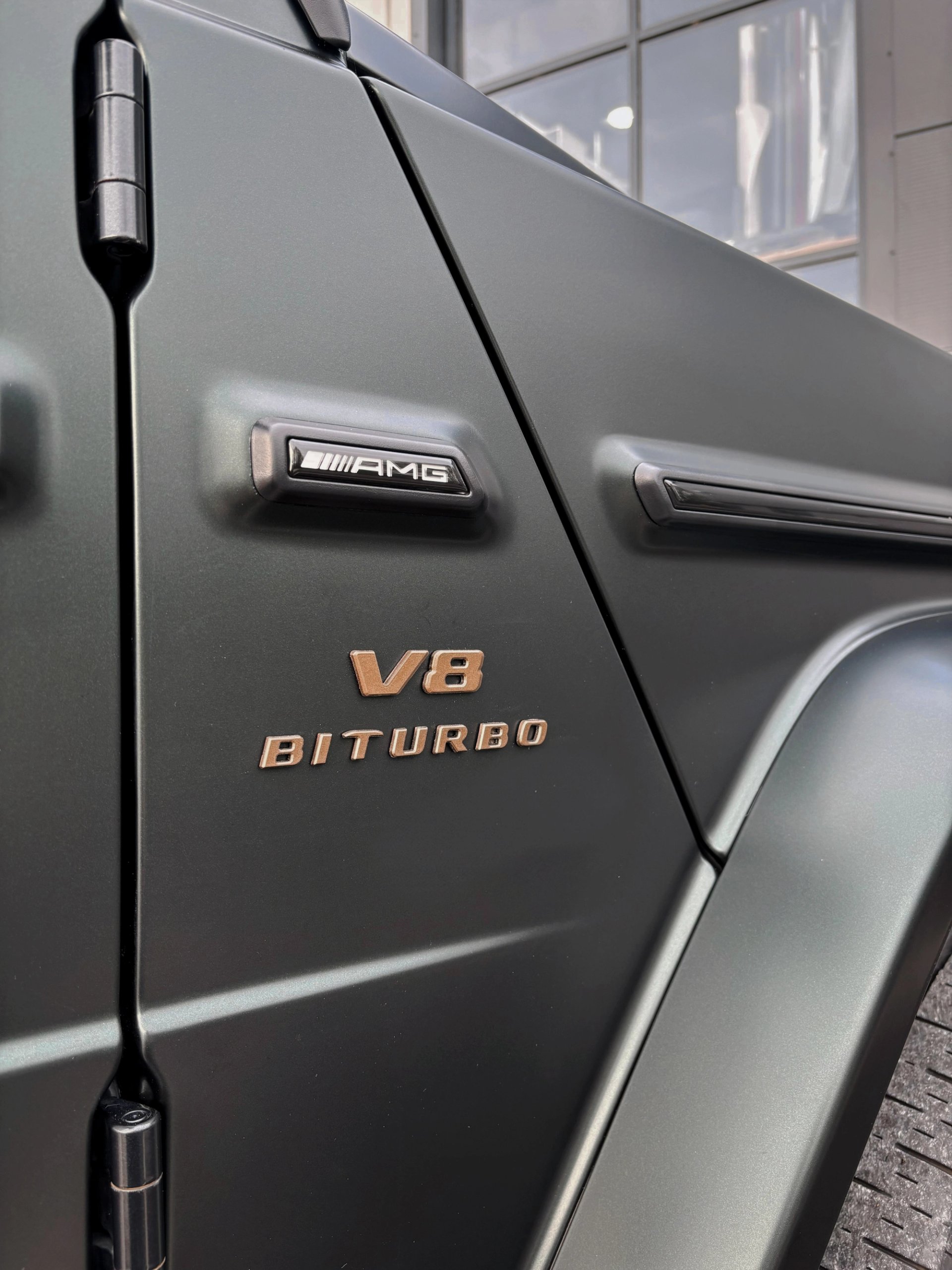 A close-up view of the matte paint and V8 Biturbo badging on a custom Forge Mercedes G63 parked outdoors.
