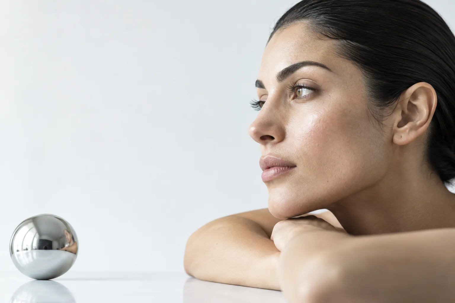 Concept editorial side portrait in soft neutral light beside a reflective sphere